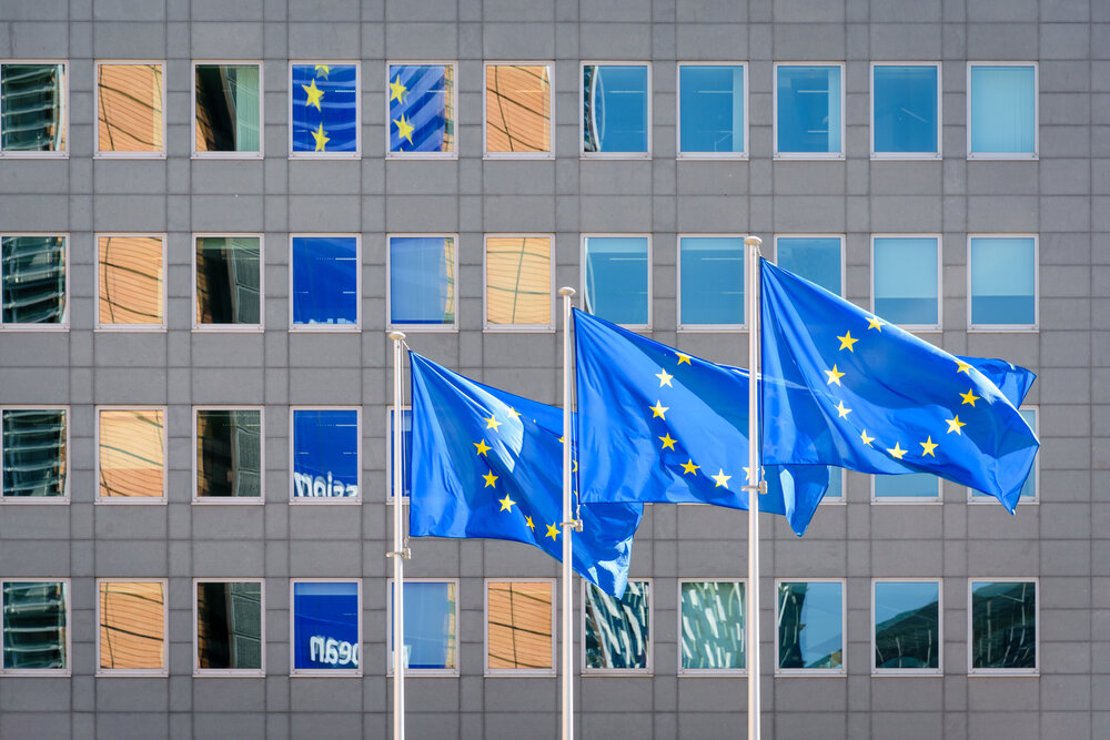Three european flags in front of the Berlaymont building