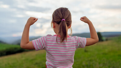 Youg girl raising her arms in a gesture of strenght